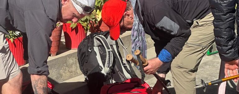 Trekkers packing red Cold Feet branded duffel bags before departing on a Nepal trek